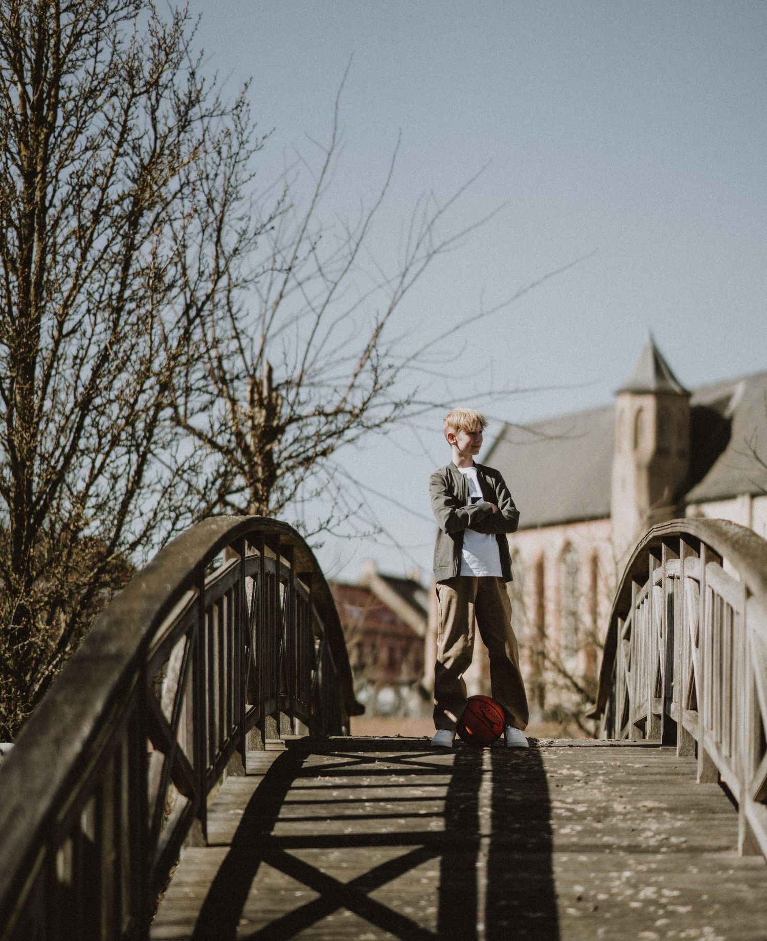 A person walks across a wooden bridge on a bright winter day.