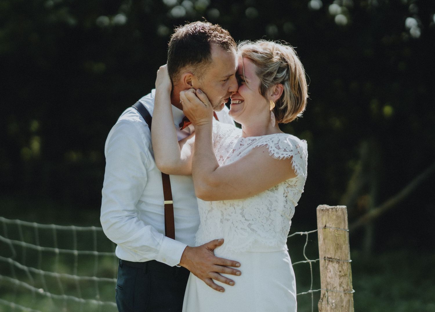 A romantic outdoor wedding moment captured between a couple in a rustic countryside setting.