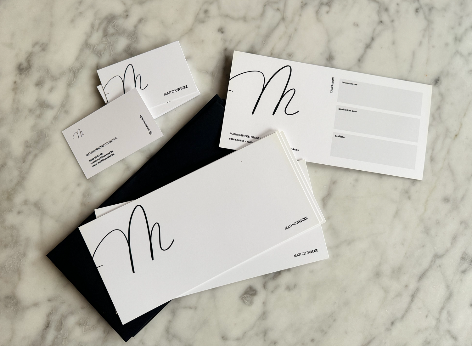 Minimalist flat lay of business cards on marble surface showing modern branding design.
