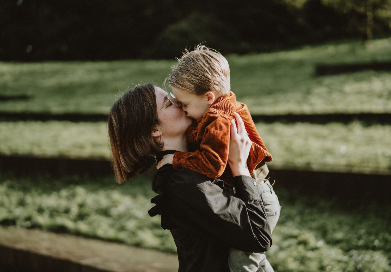 Tender outdoor moments between parent and child in warm autumn lighting.