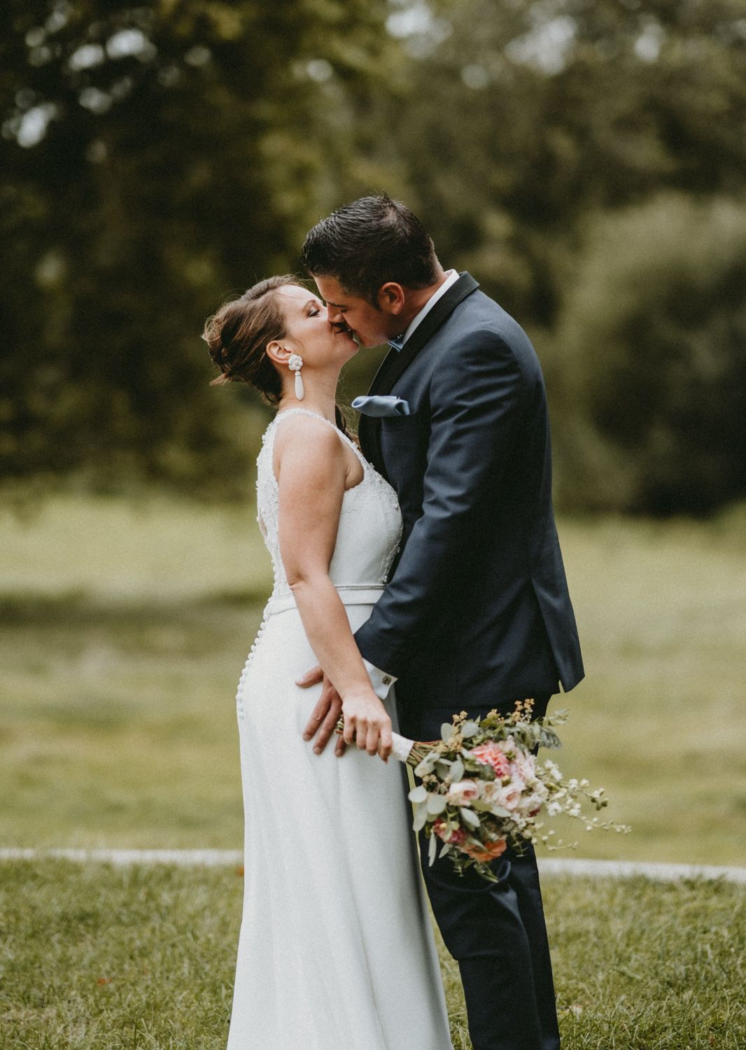 An intimate wedding portrait of a couple sharing a tender moment with a bridal bouquet.