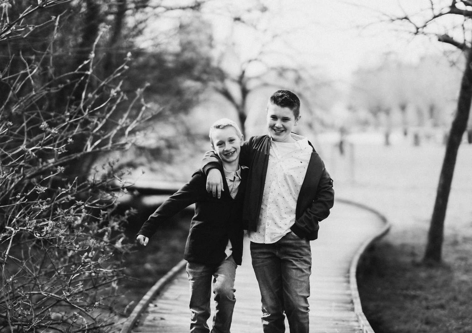 Black and white romantic photos of a couple walking together on a wooded path.