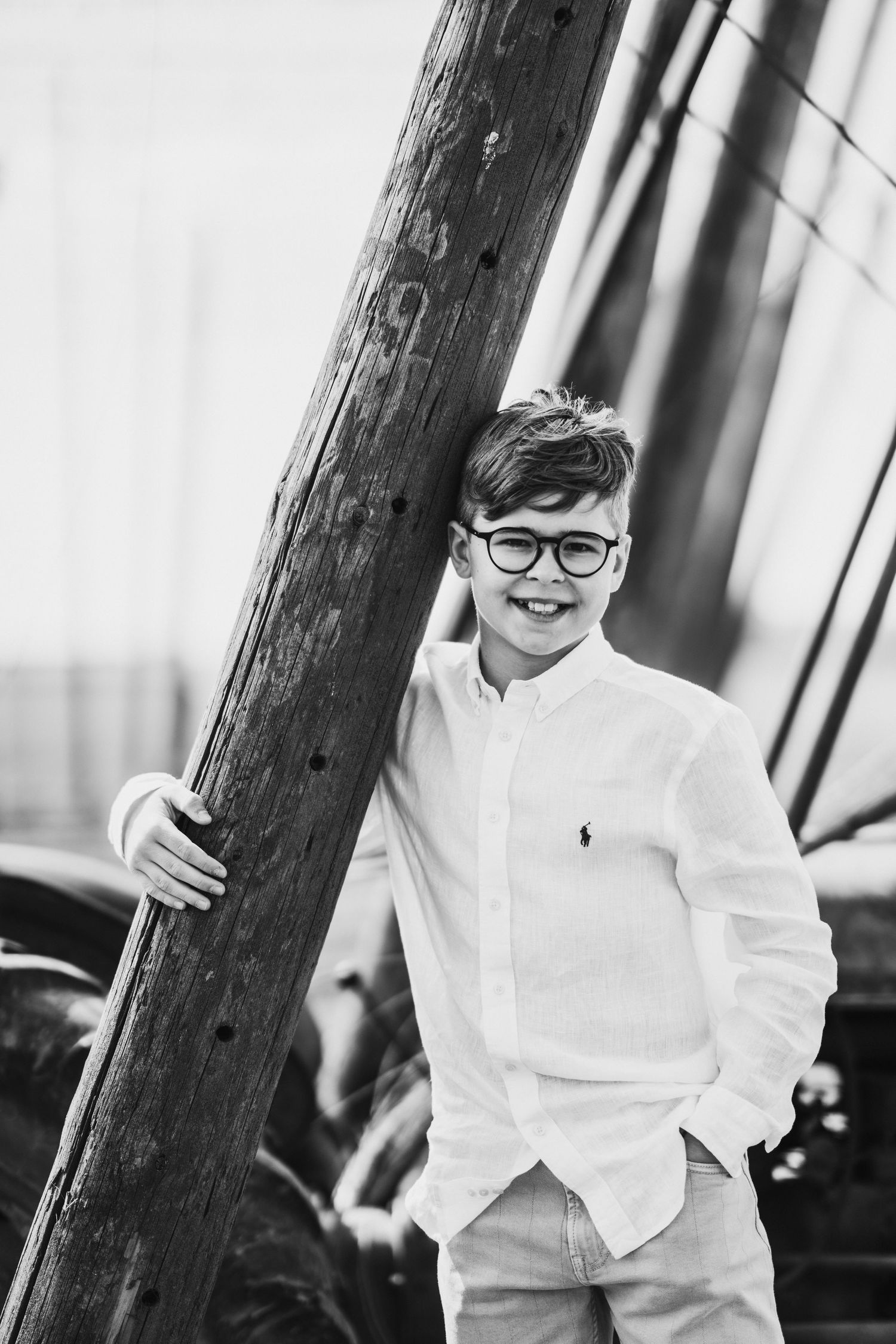 Black and white portrait series showing playful expressions against a wooden post backdrop.