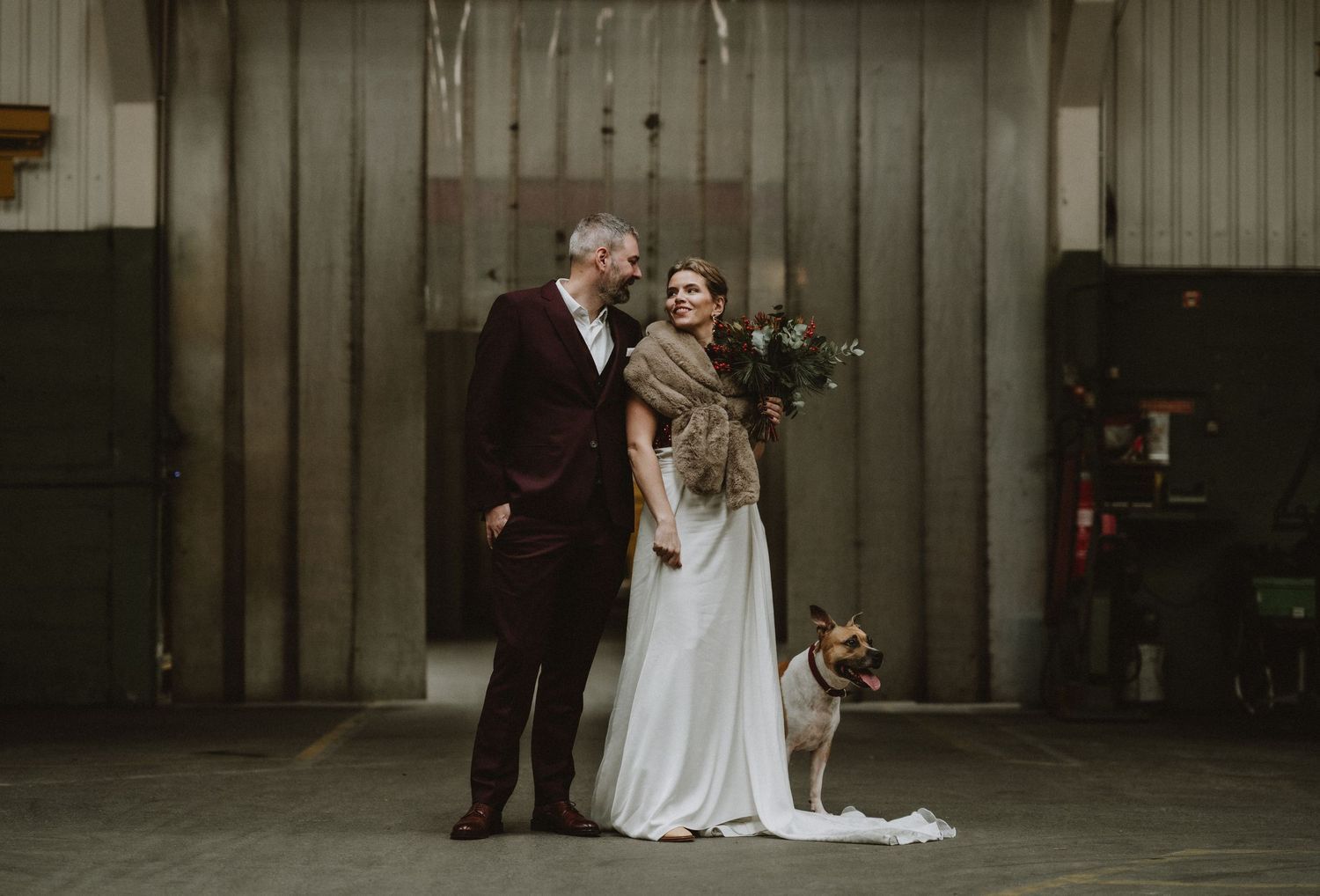 Wedding celebration in an industrial venue with rustic wooden wall backdrop.