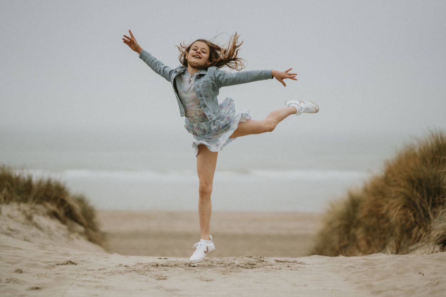 Person jumping joyfully on a misty beach at dawn.