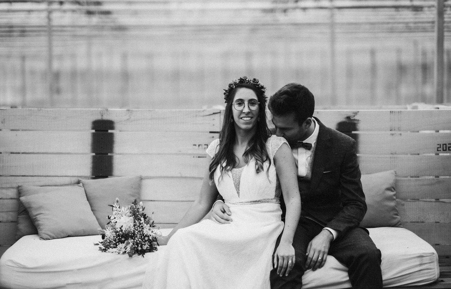 Wedding couple shares romantic moments on rustic wooden bench setting.