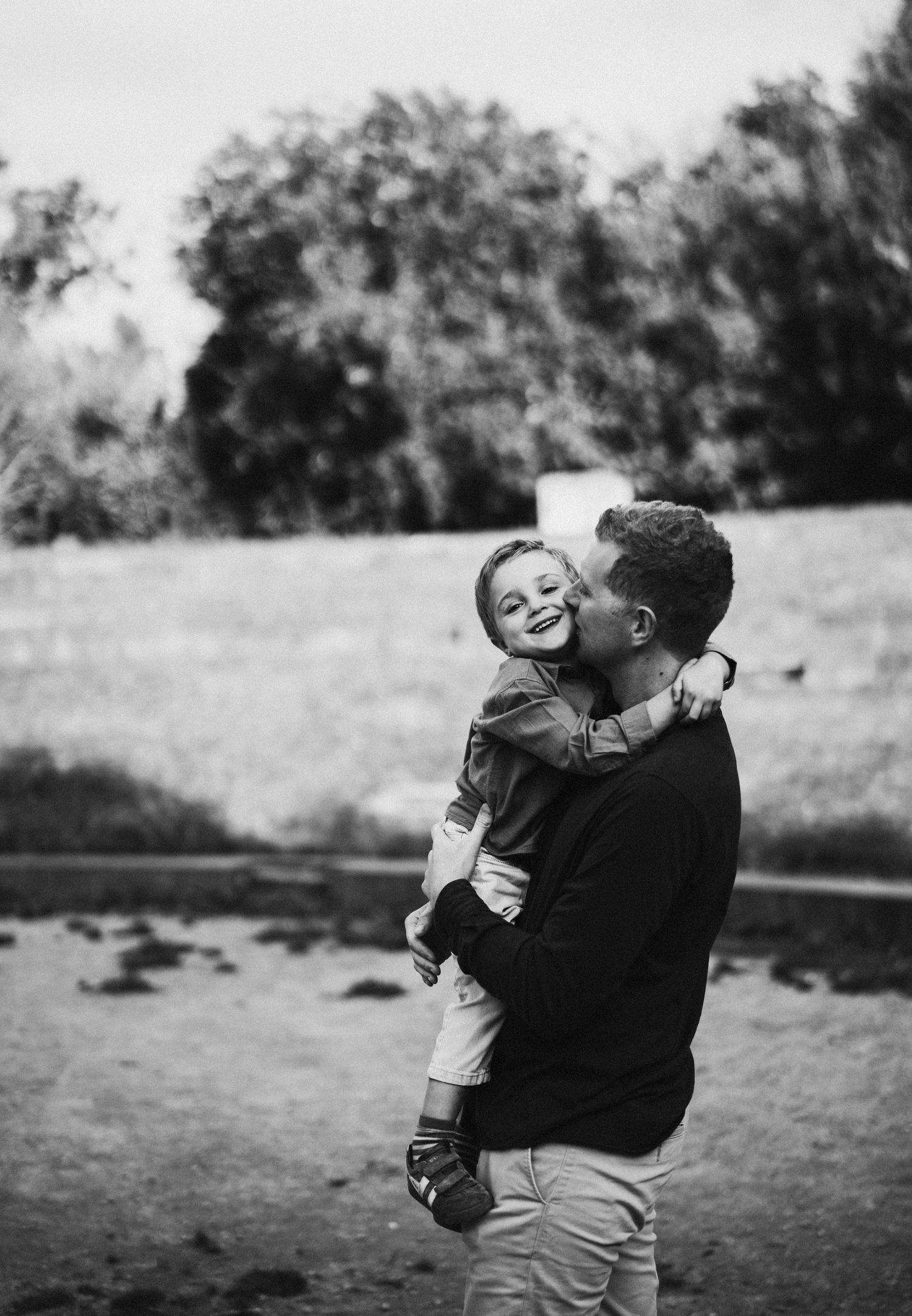 Black and white photo series showing playful embraces and laughter in an outdoor setting.
