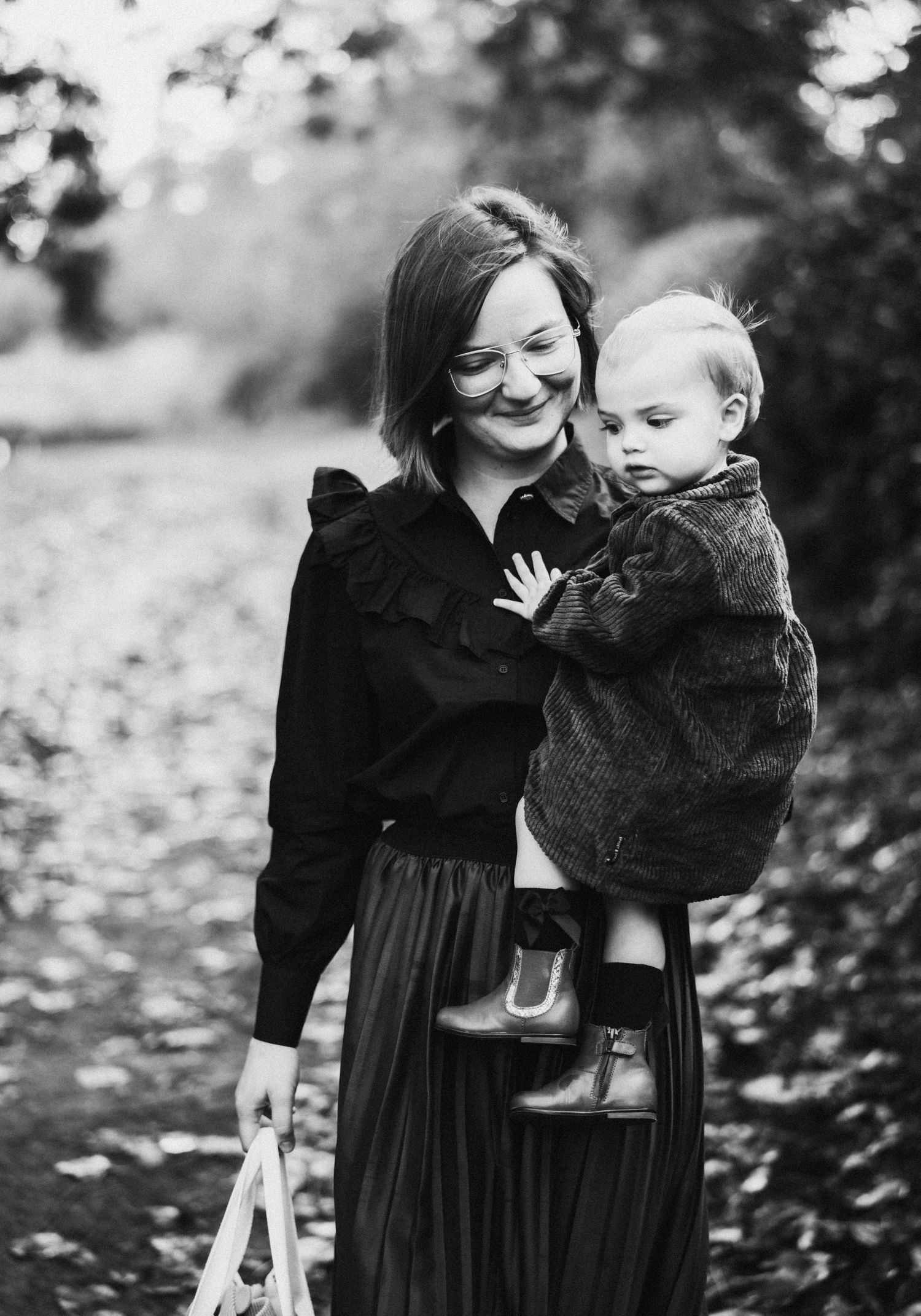 Black and white portraits capturing tender moments between parent and child among fallen leaves.