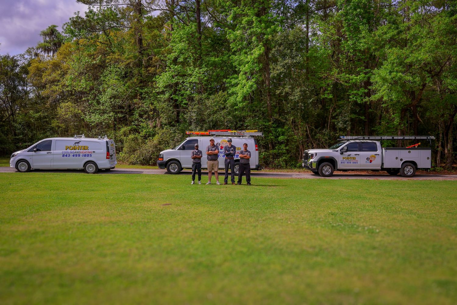 Wide view of service vehicles and team members gathered in a park-like setting.