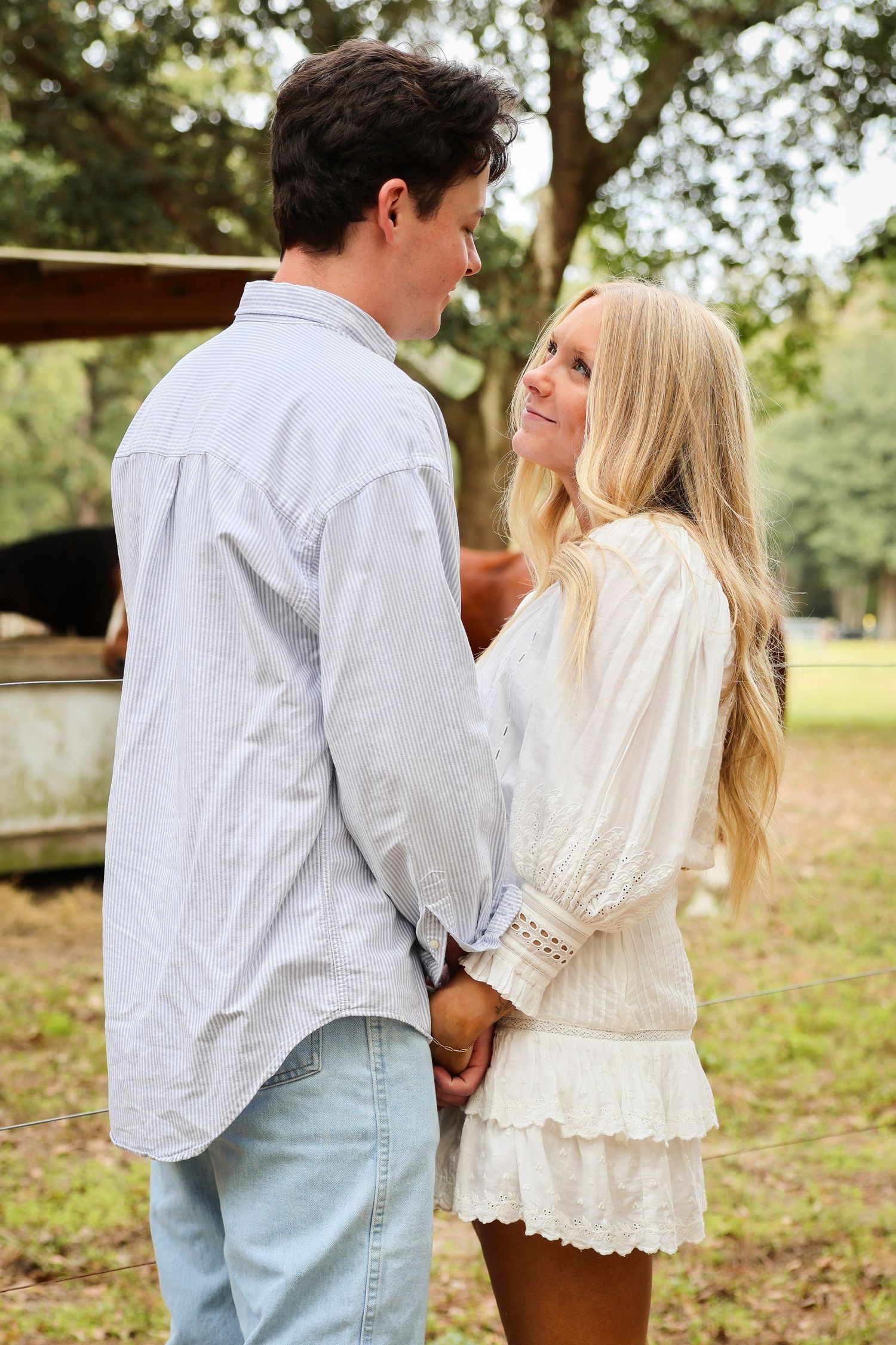 A romantic moment captured between two people in white and denim clothing outdoors.