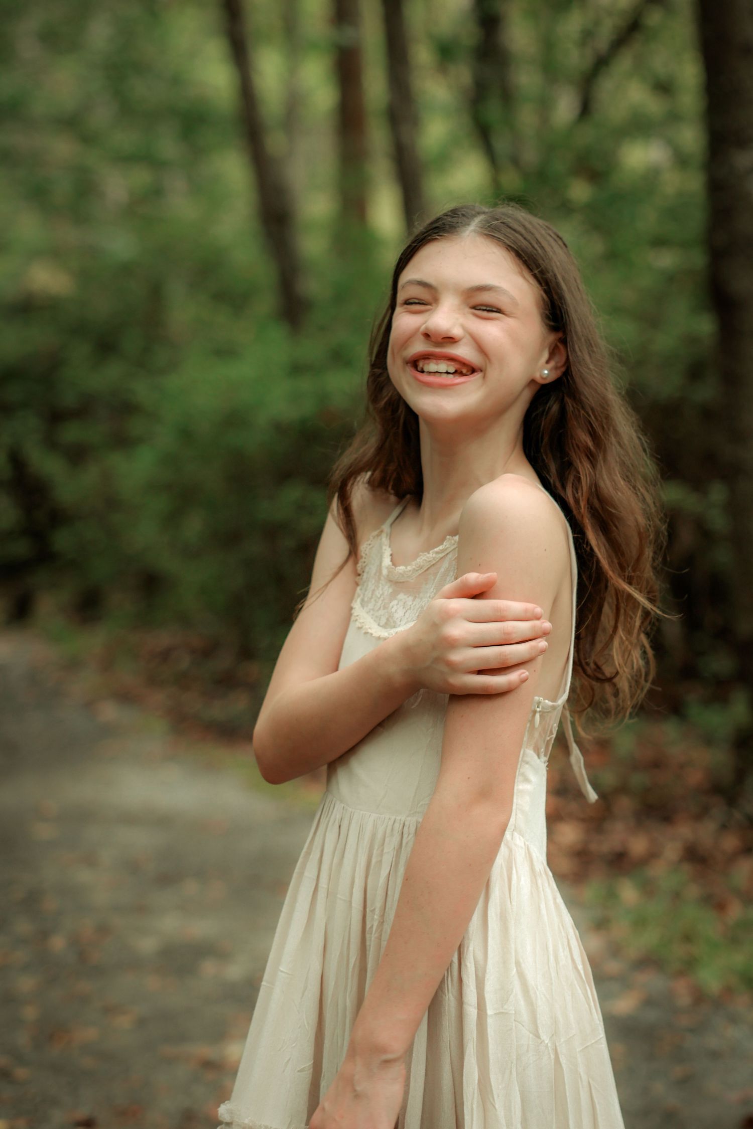A joyful portrait in a forest setting featuring a cream-colored vintage dress.
