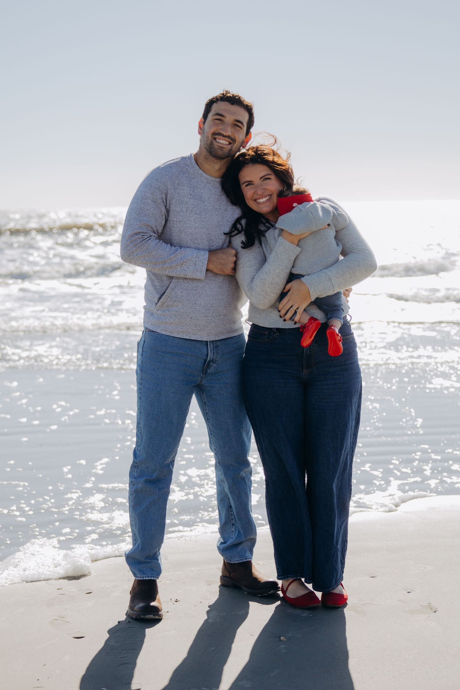 Couple enjoying a sunny day together at the beach with waves in the background.