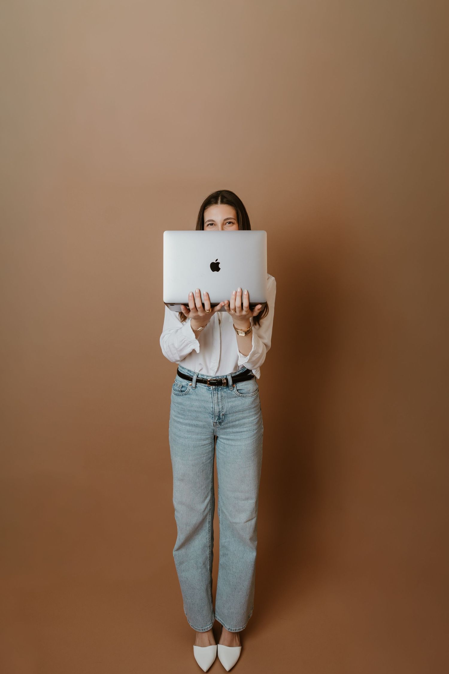 Playful series showing someone hiding behind a MacBook laptop against beige background.