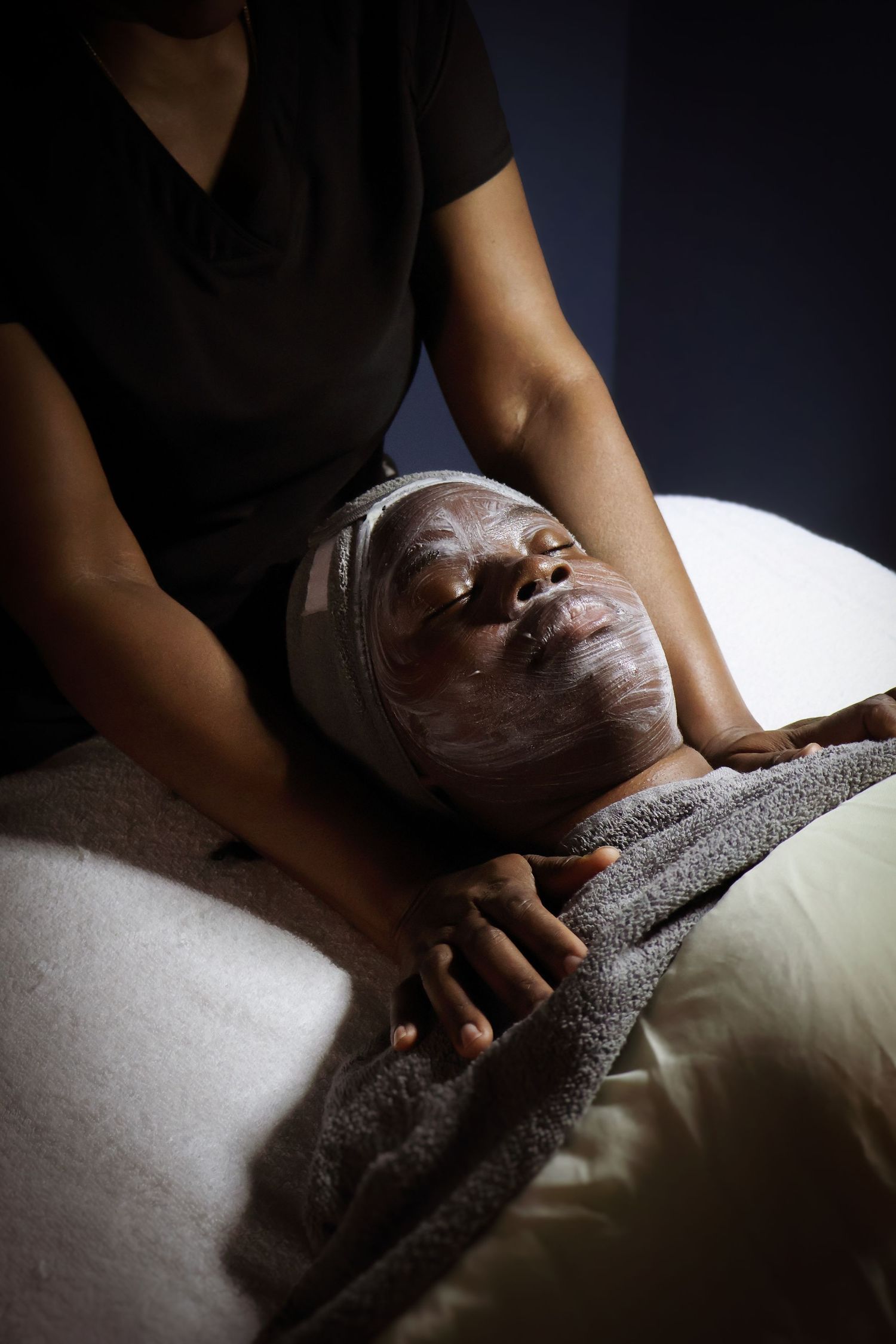 Relaxing spa facial treatment session with white cream application in low lighting.