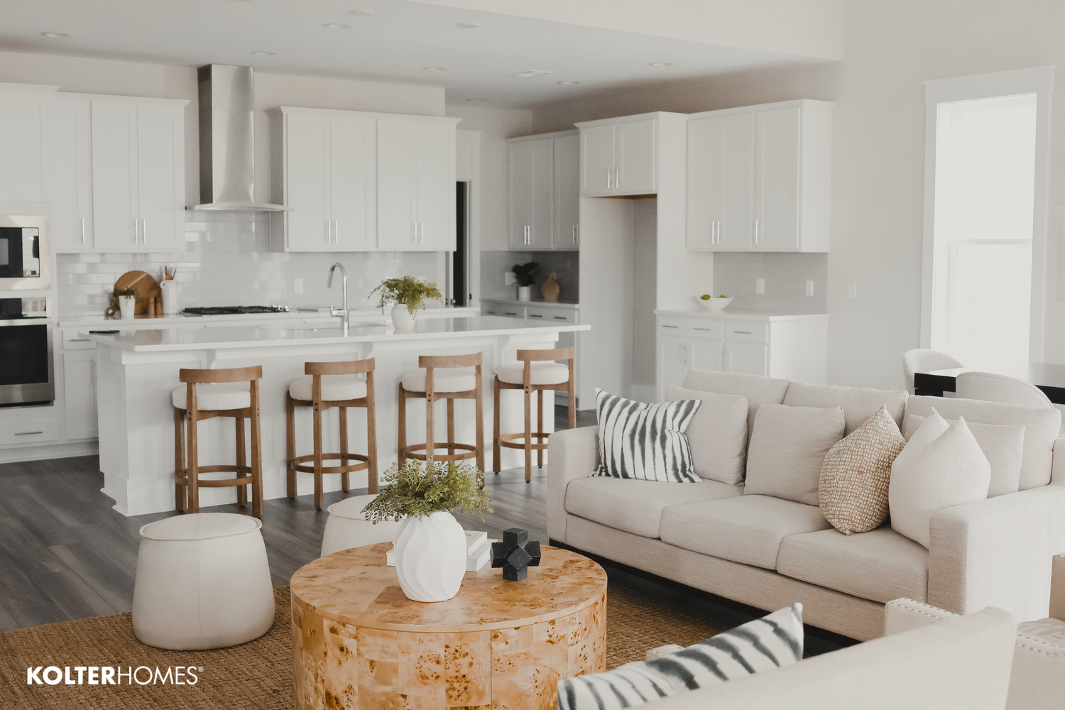 Luxurious white kitchen and living space with natural wood accents.