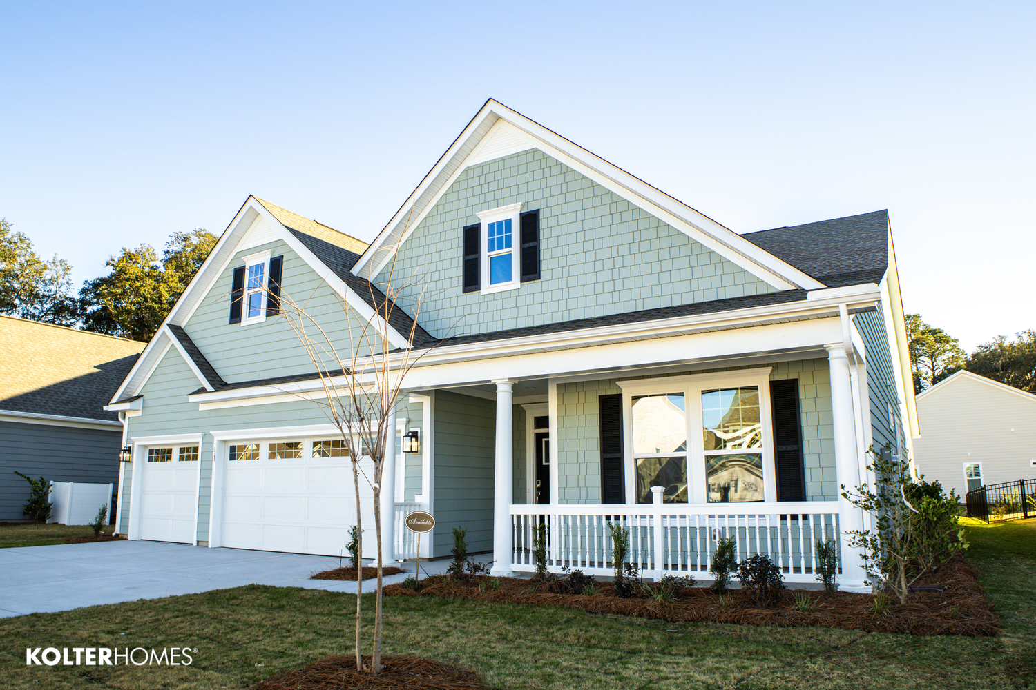 Light blue craftsman style home with white trim, front porch and two-car garage.