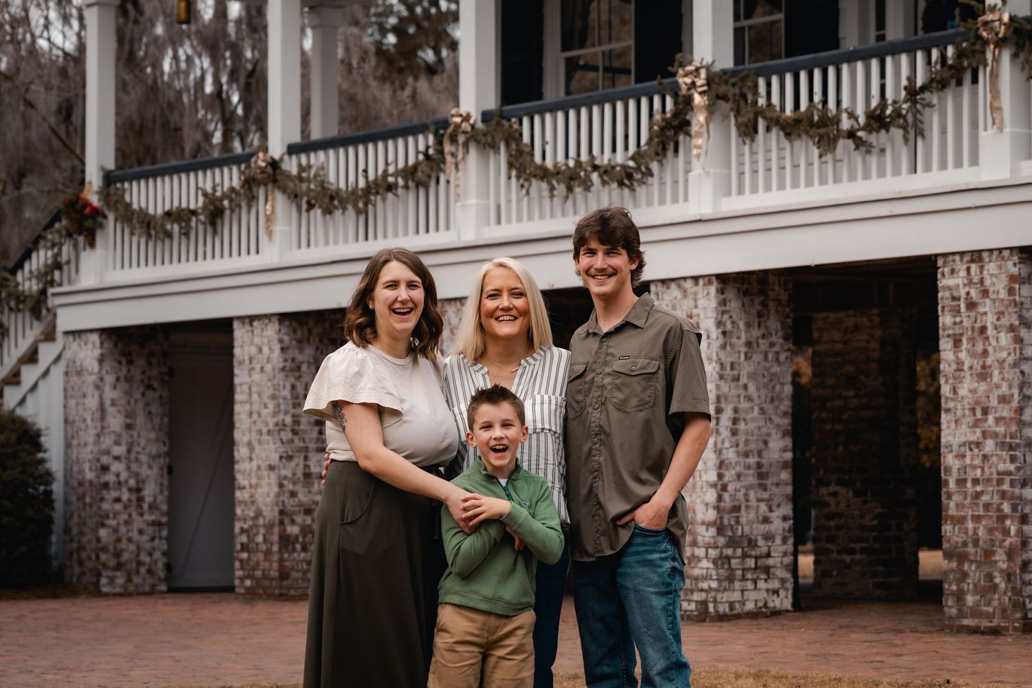 Outdoor gathering on brick porch of southern style mansion with white columns.