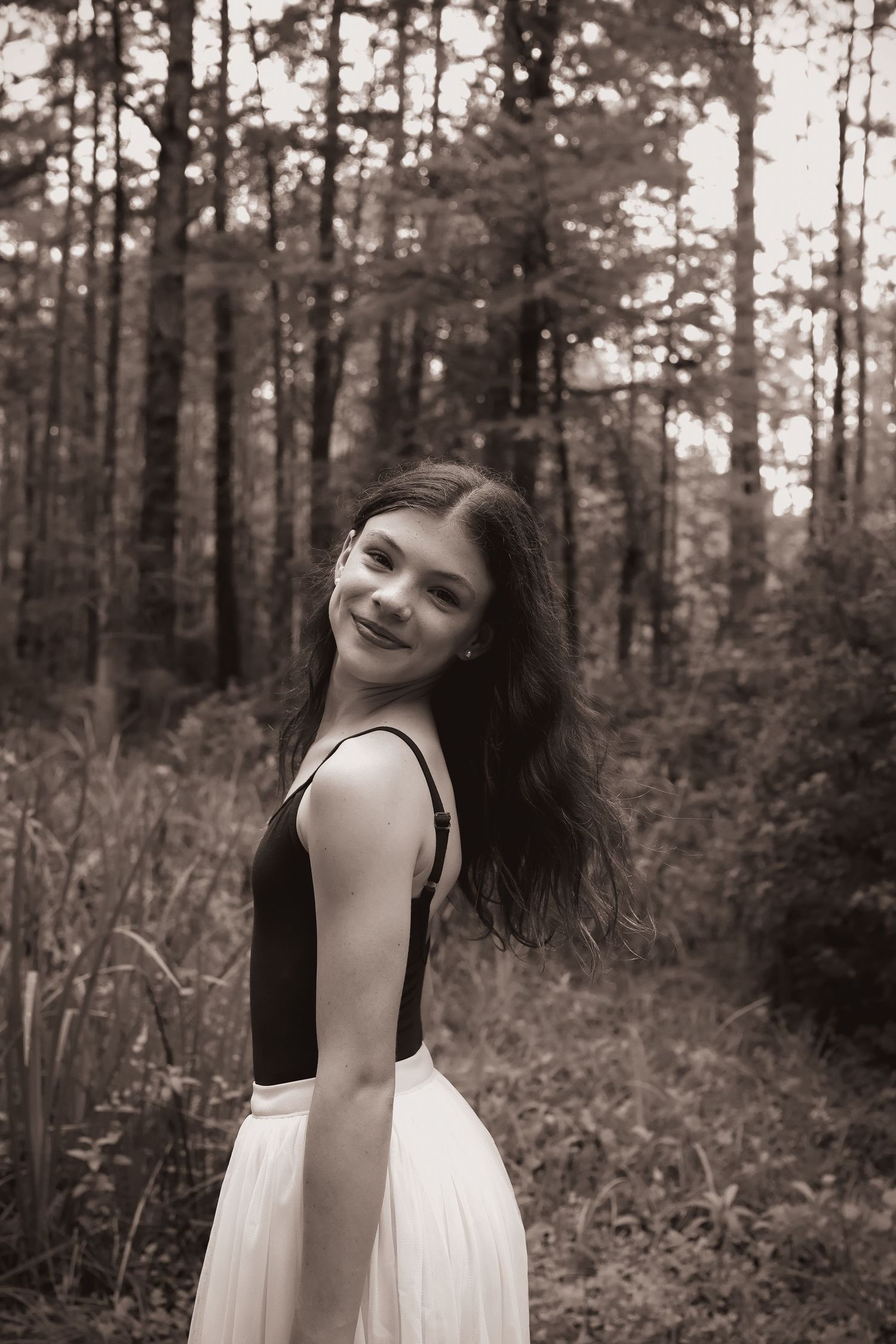 Artistic black and white portrait series showing joyful expressions in a forest setting.