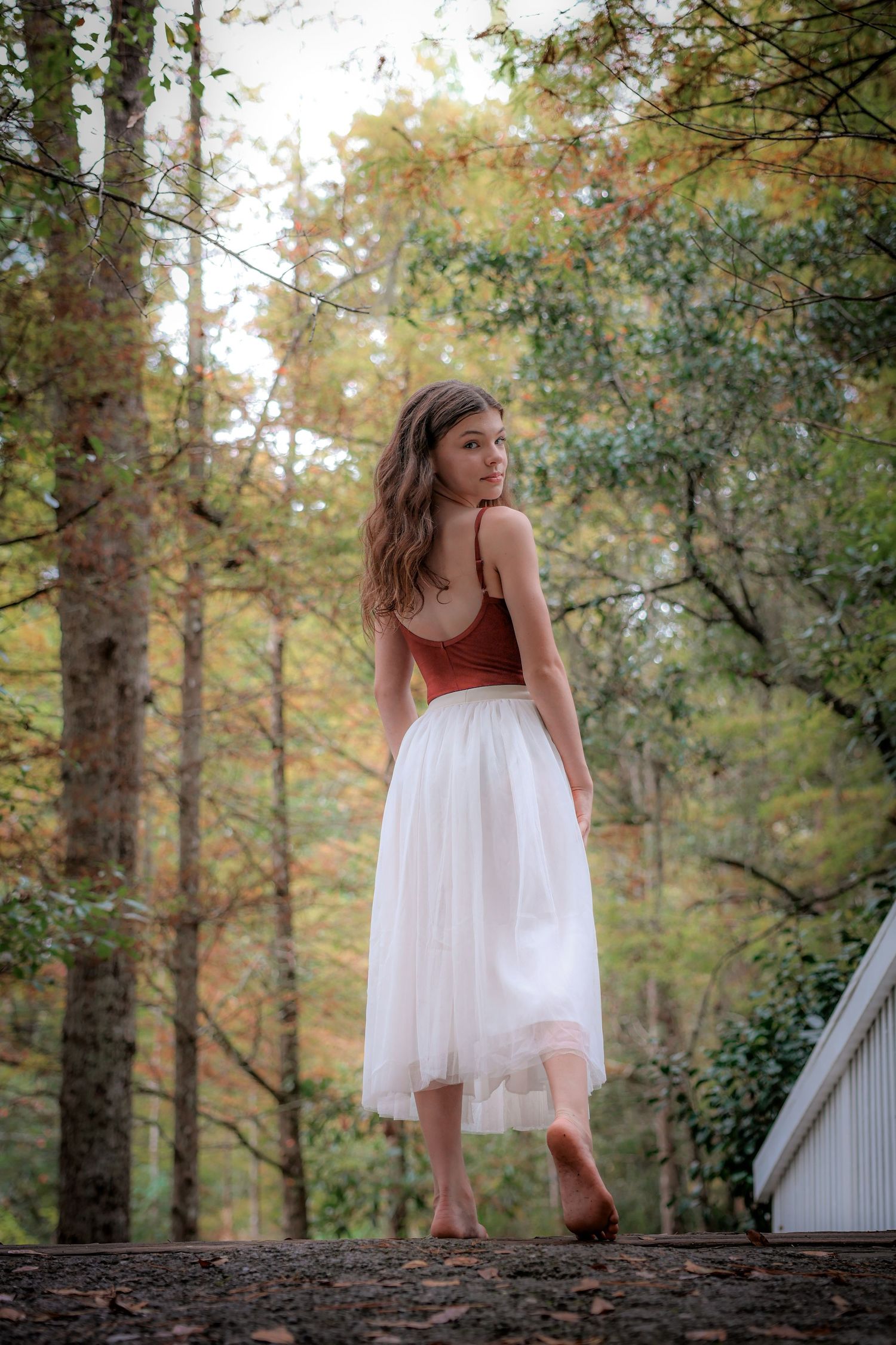 Ethereal portrait sequence of someone in a white dress dancing on a rustic log in autumn woods.