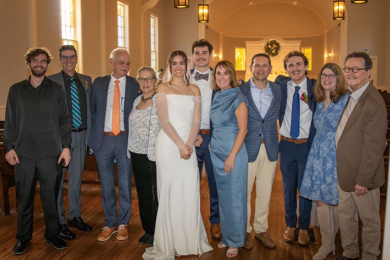 Large group photo of wedding guests inside elegant venue with warm lighting.