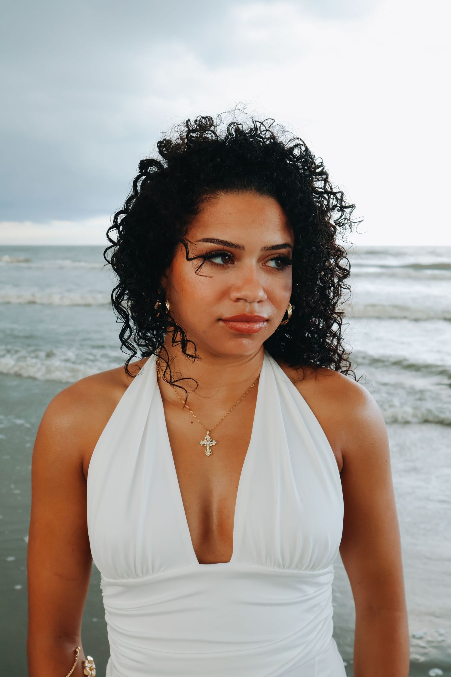 Beachside portrait featuring a white halter dress and natural curly hair.