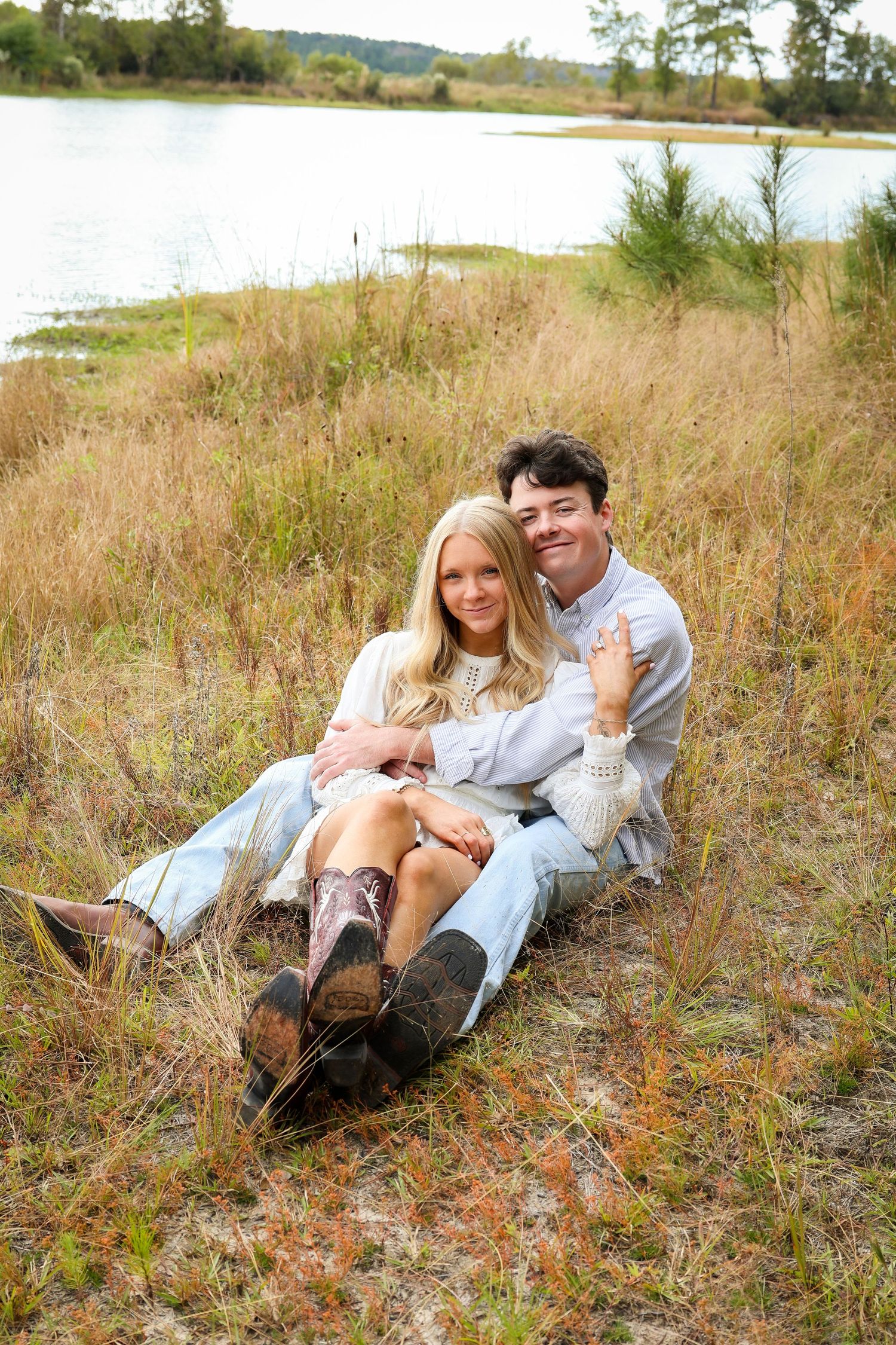 A couple relaxing together on grassy hillside in casual clothing.