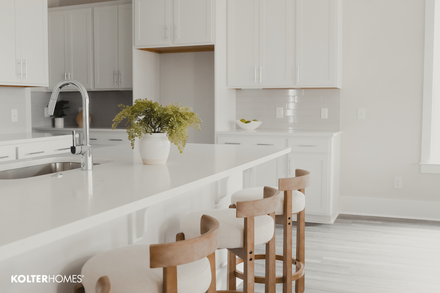 Bright contemporary kitchen featuring white cabinets and wooden counter stools.