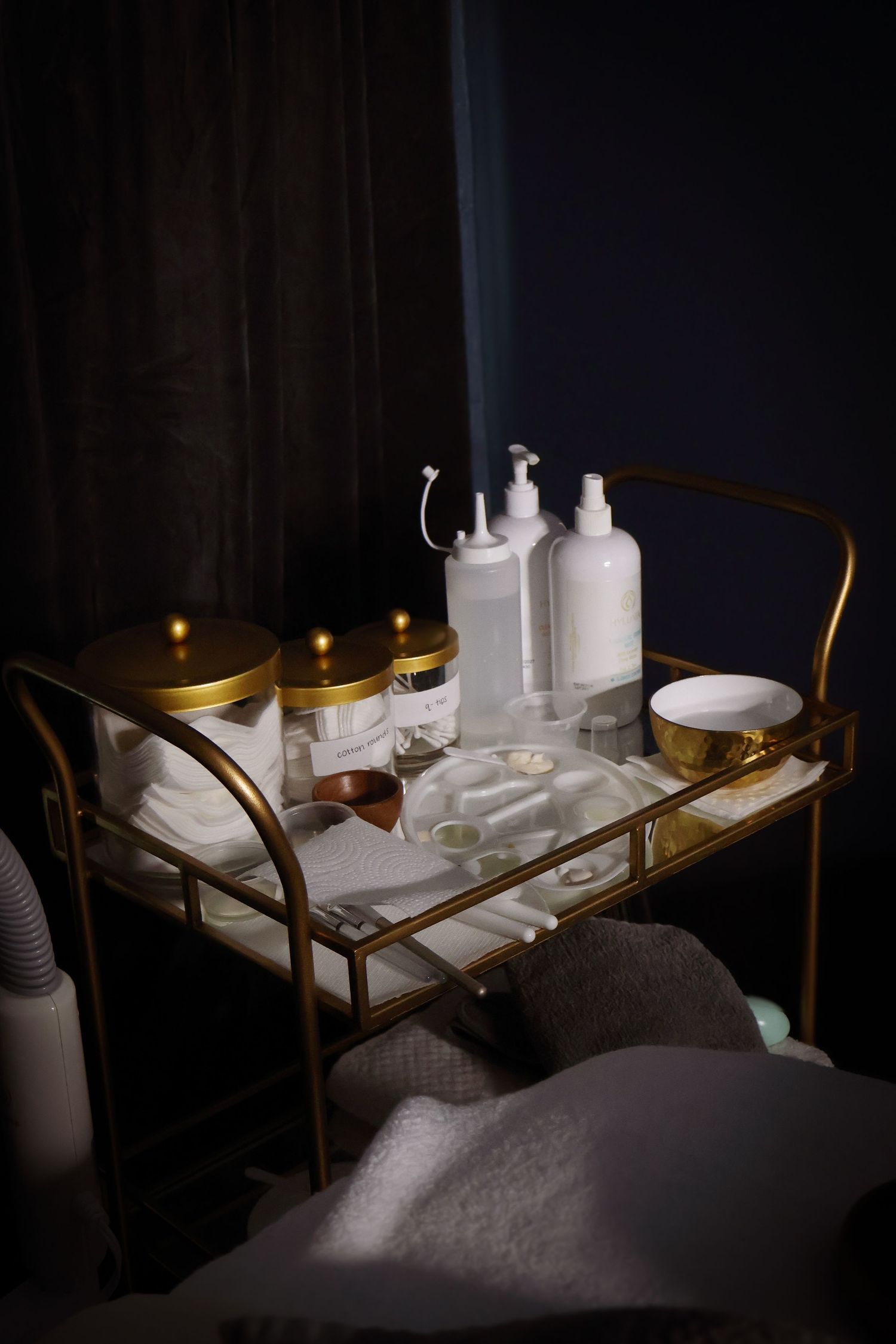 White skincare products and bottles arranged on a glass tray in a dimly lit spa setting.