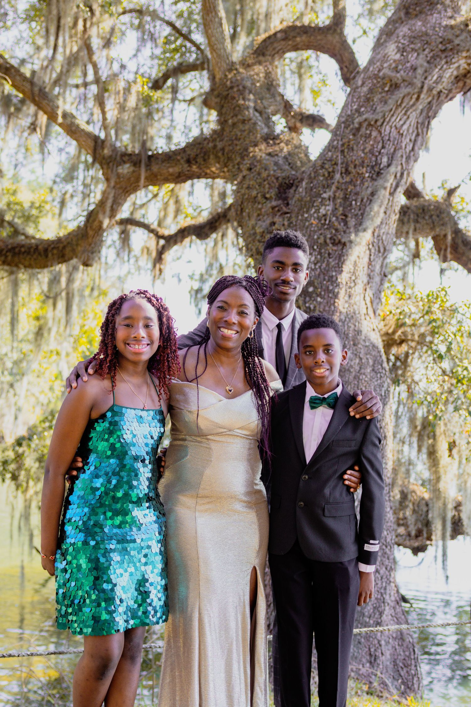 Group photo outdoors with Spanish moss trees, featuring sparkly green and formal attire.