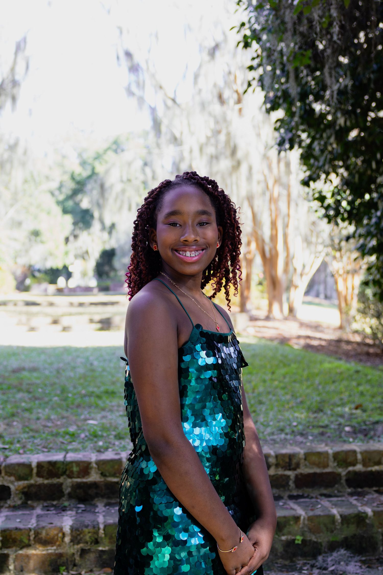 Outdoor portrait featuring sparkly teal sequin dress against natural background.