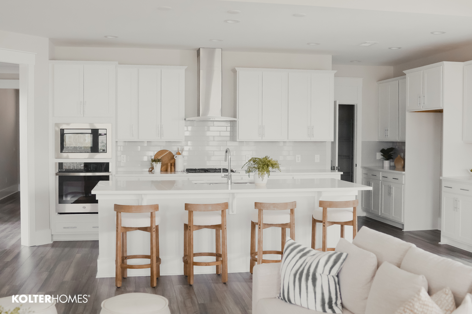 Modern white kitchen with wood bar stools and open concept design.