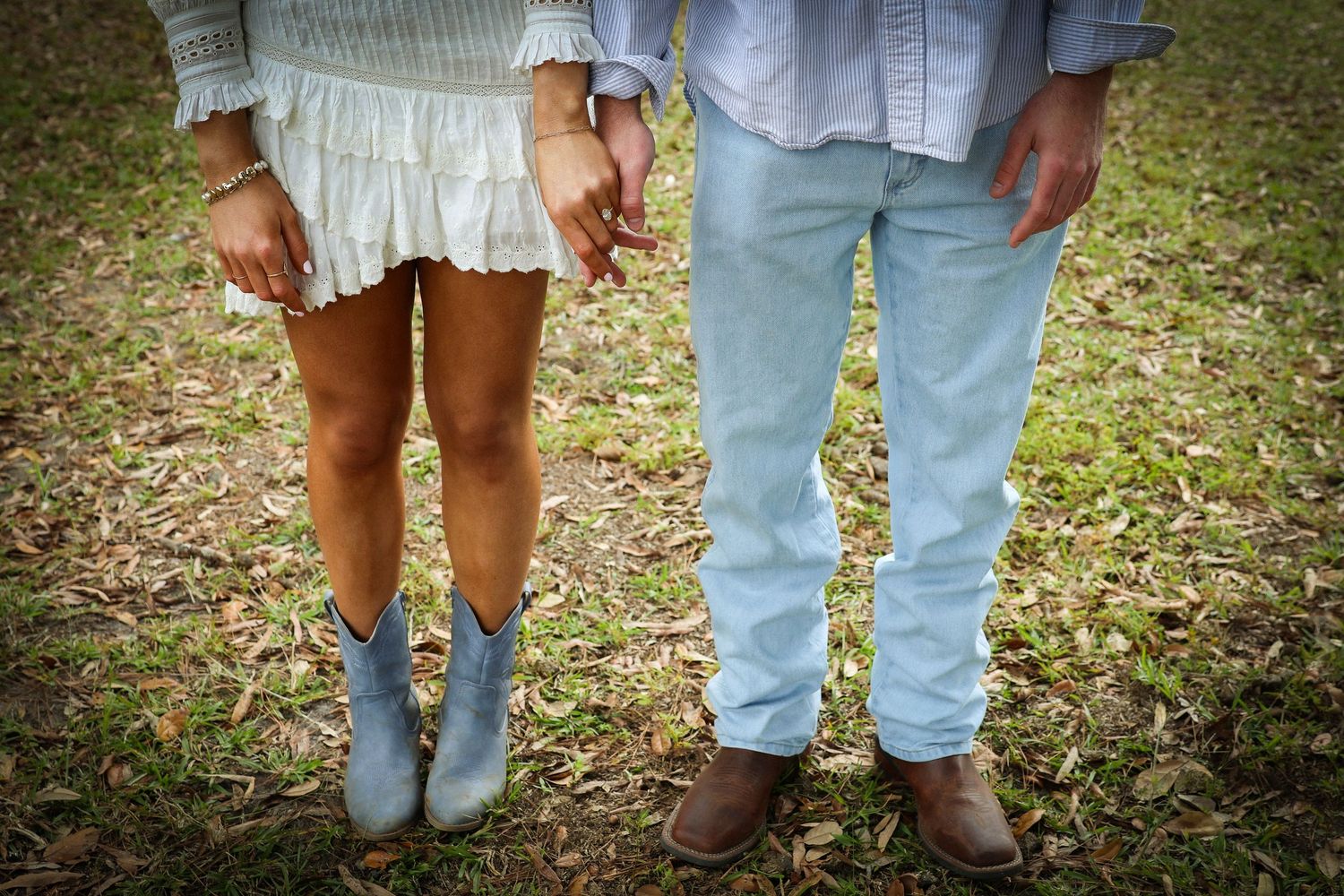 Close-up view of casual footwear and jeans on people standing in grass.