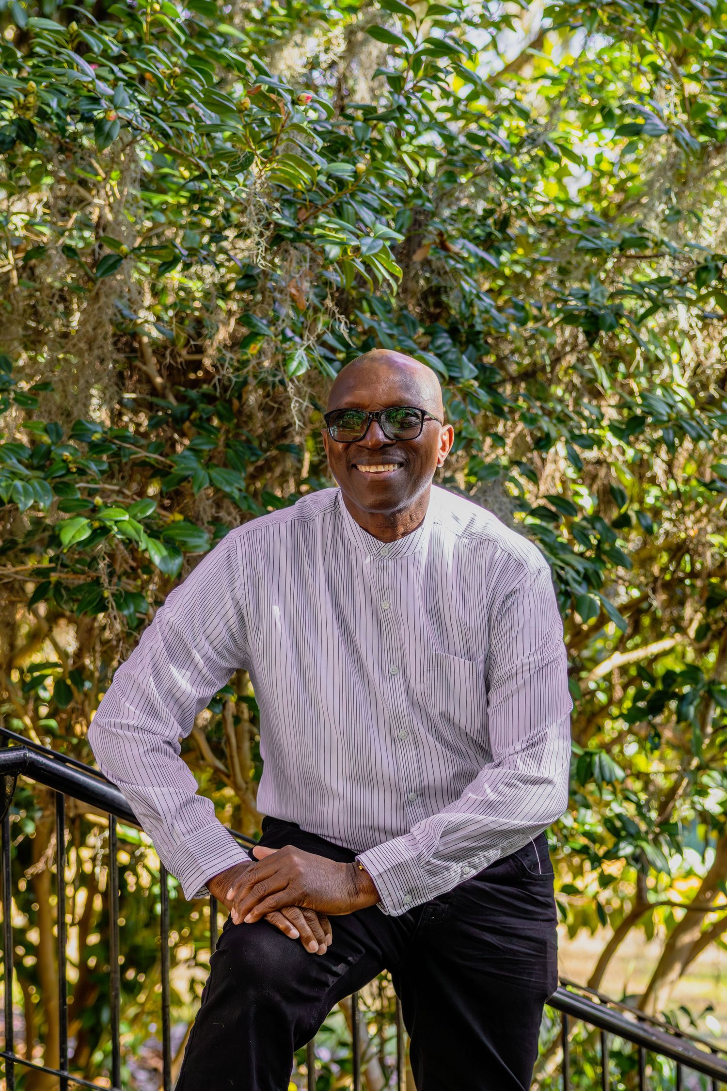 Person in a white striped shirt and dark pants sits casually on outdoor steps.