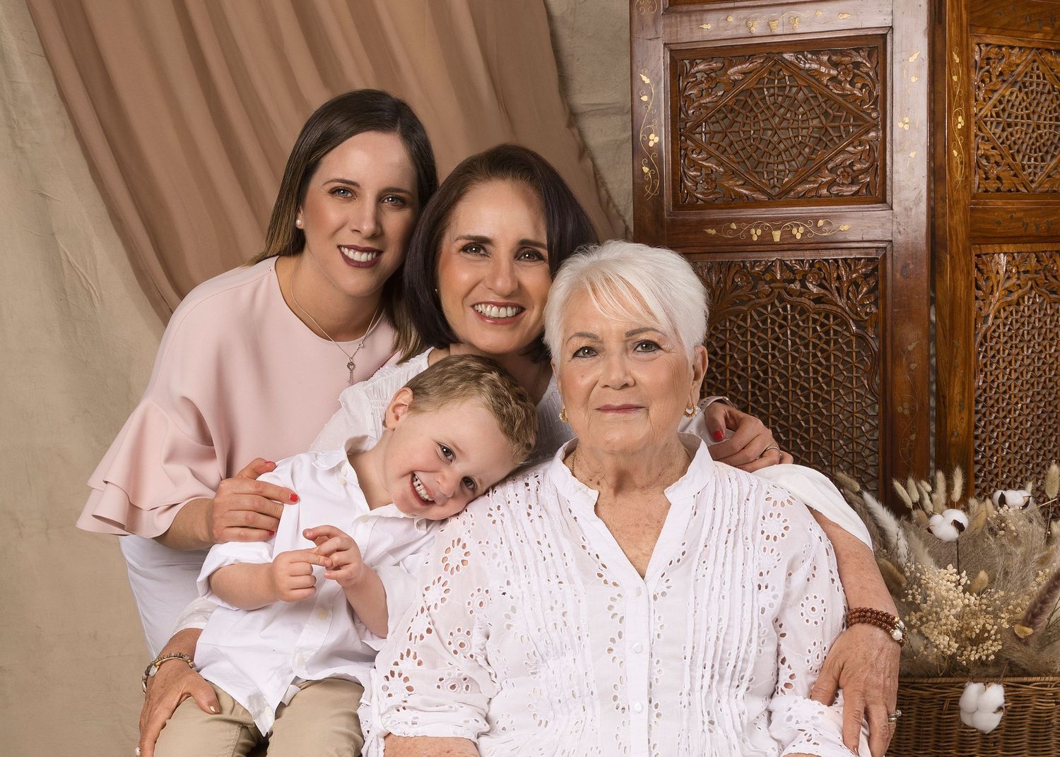 Multi-generational family portrait featuring grandmother, mother, daughter, and young grandchild.