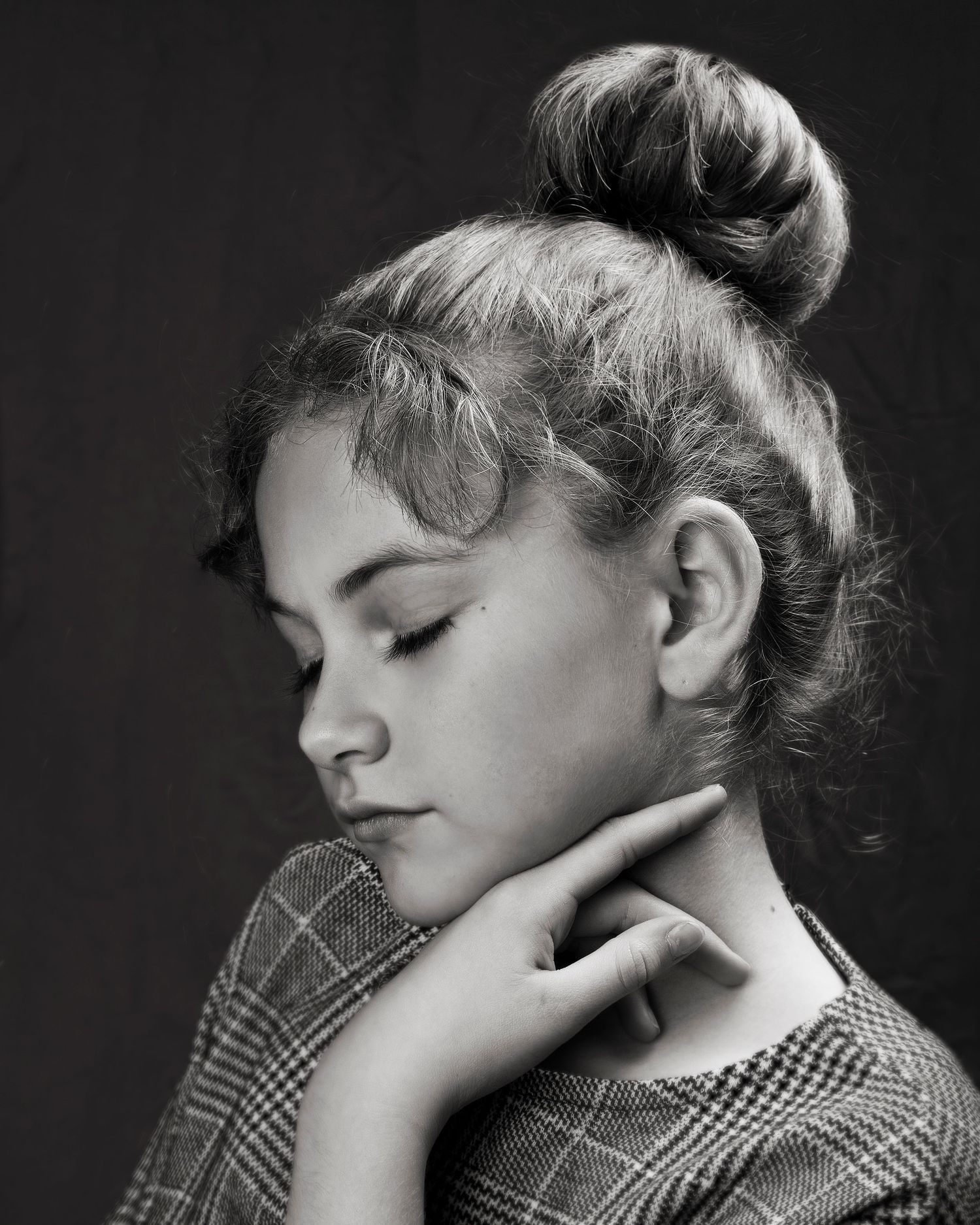 Black and white profile portrait of a young girl with hair in a bun, eyes closed.