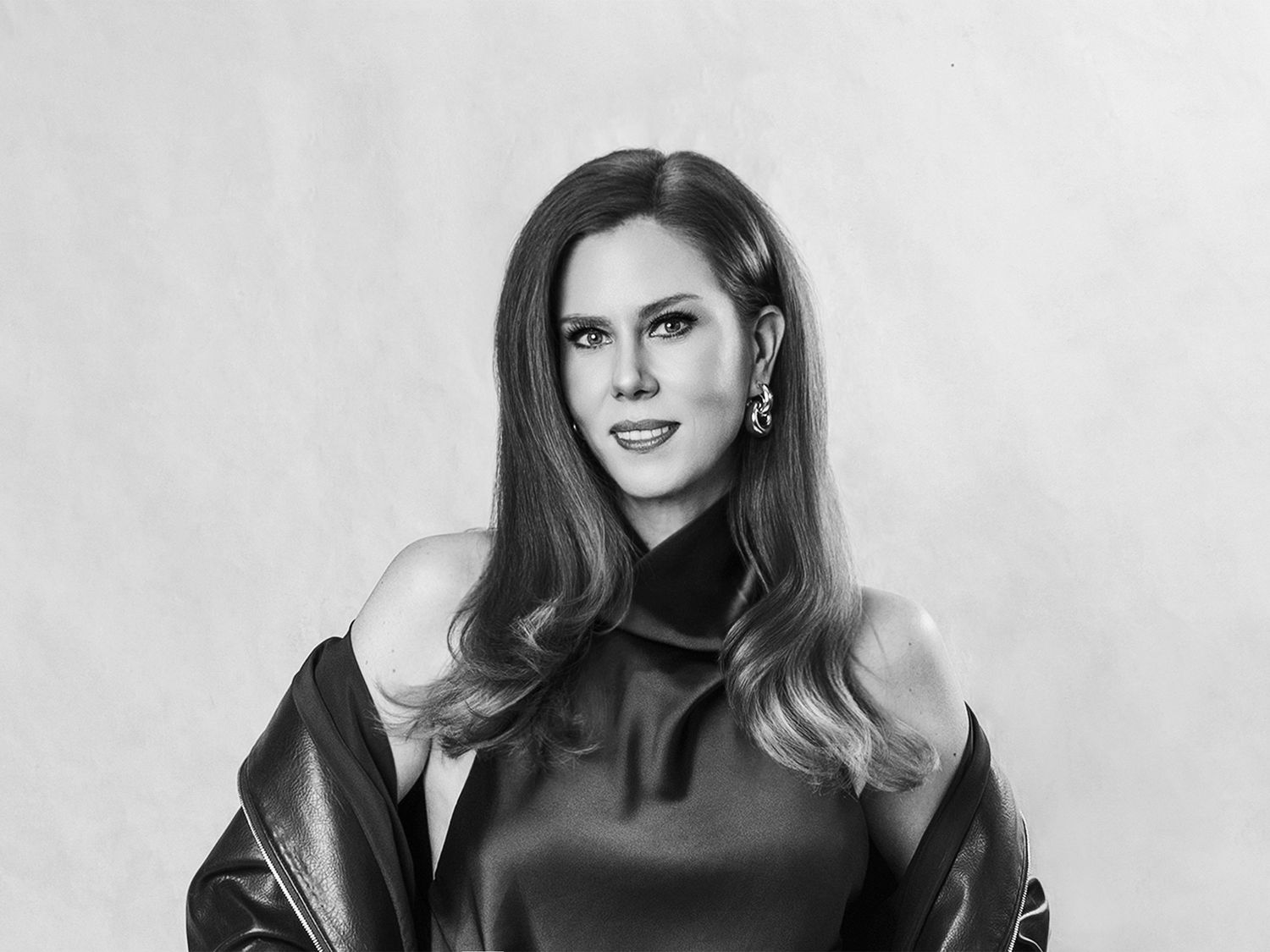 Elegant black and white portrait of woman in off-shoulder satin dress with leather jacket.