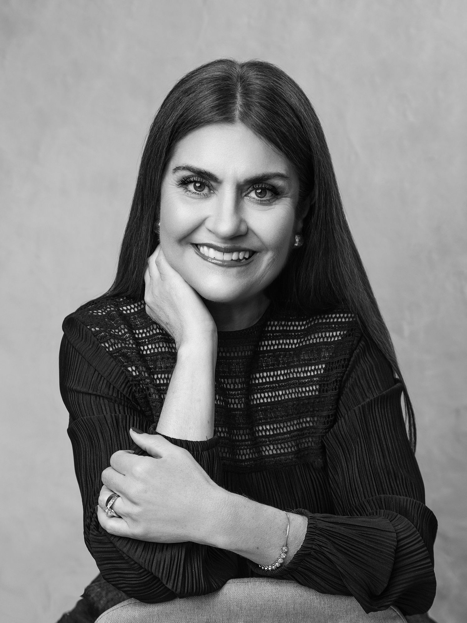 Woman in black lace top posing elegantly in a black and white professional portrait photo.
