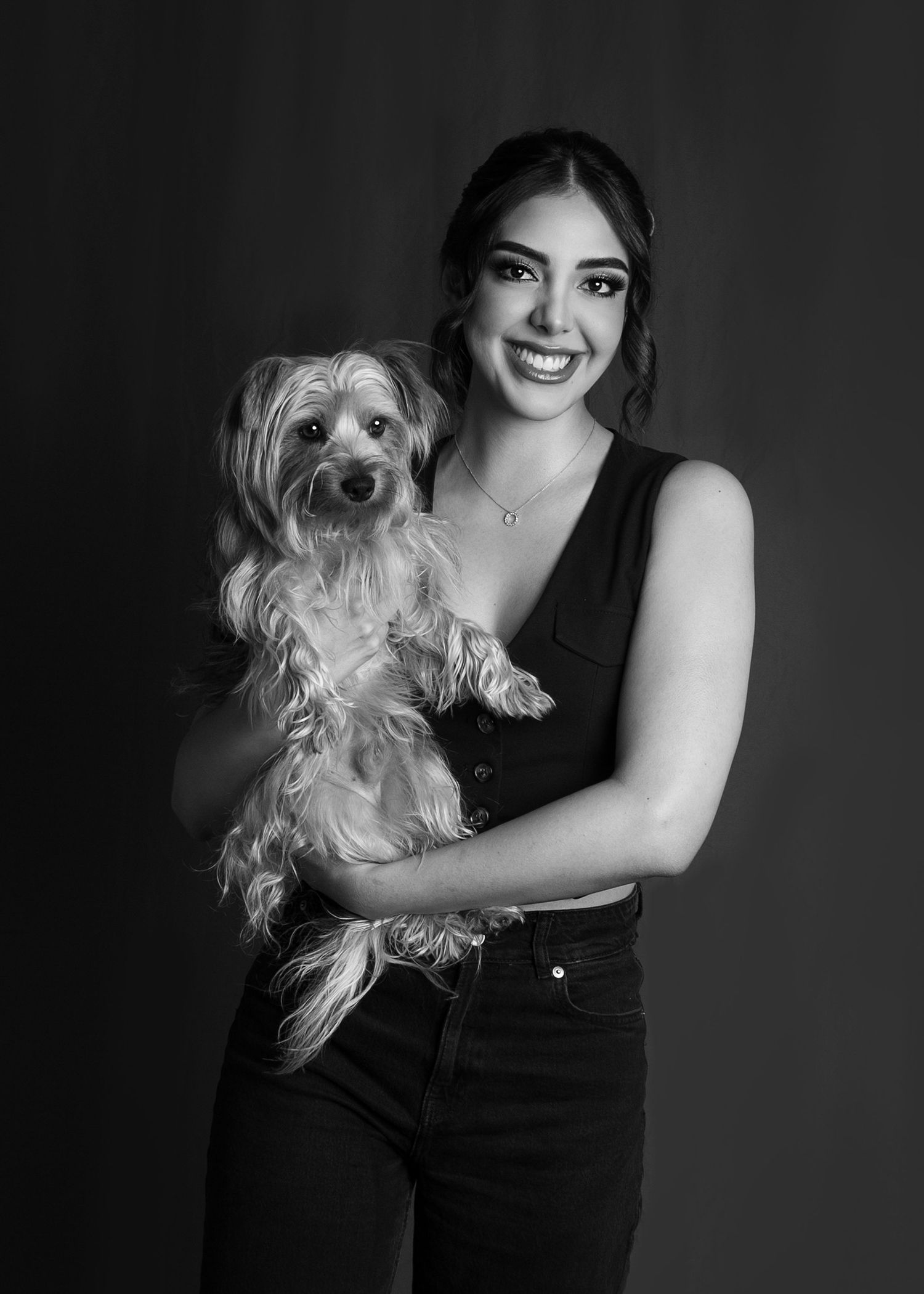 Black and white portrait of a smiling young woman holding a small Yorkshire Terrier dog.