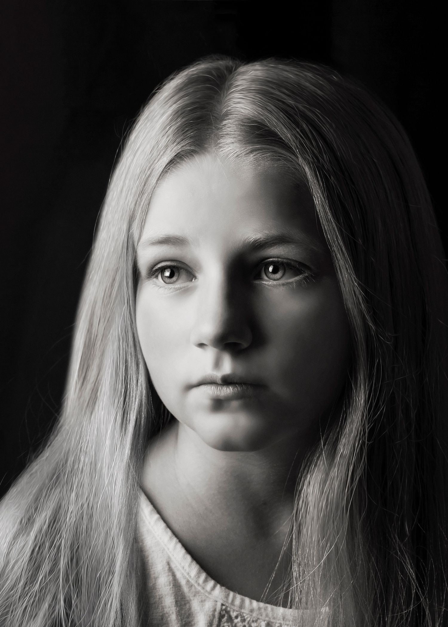 Black and white close-up portrait of a blonde teenage girl with long straight hair and calm expression.