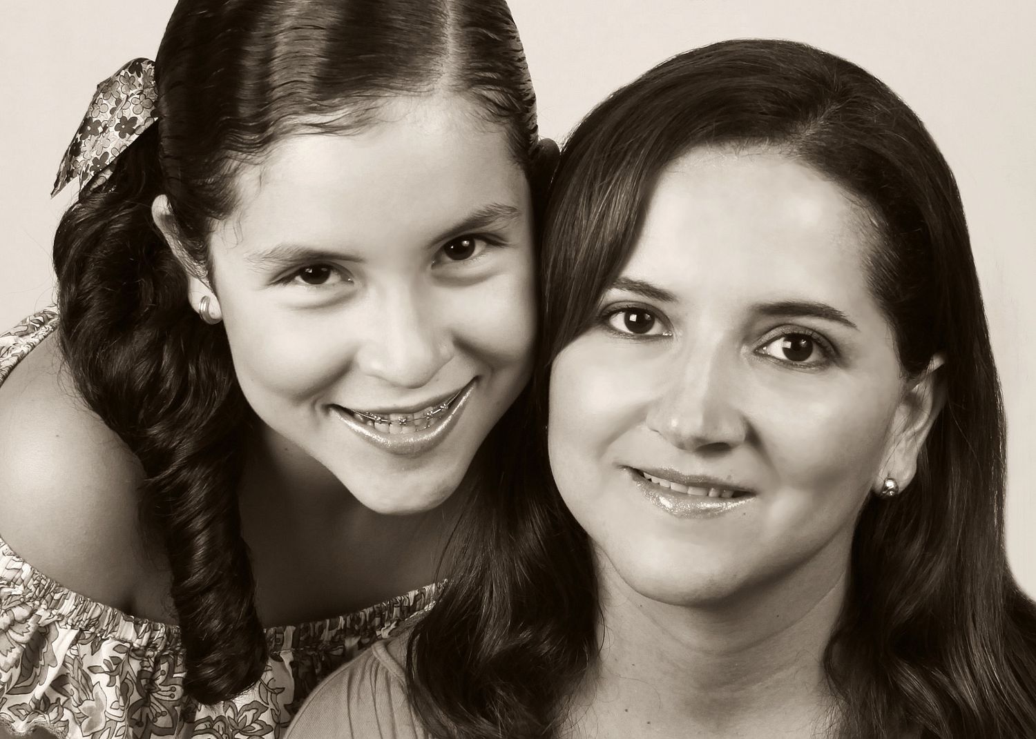 Black and white portrait of a smiling mother and daughter posing cheek to cheek together.