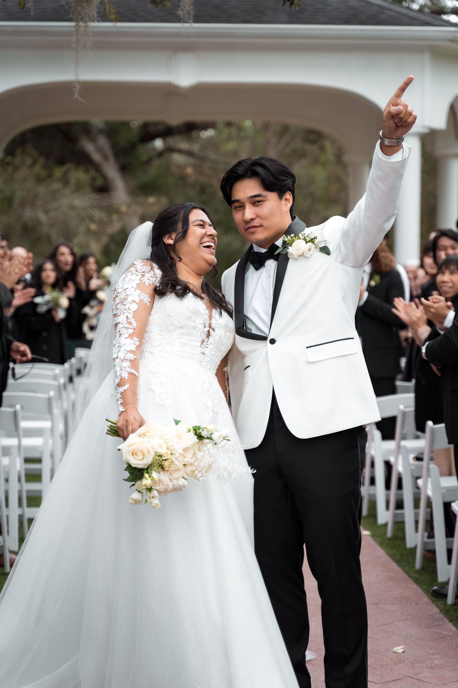 Newlyweds celebrate joyfully while walking down aisle after ceremony.