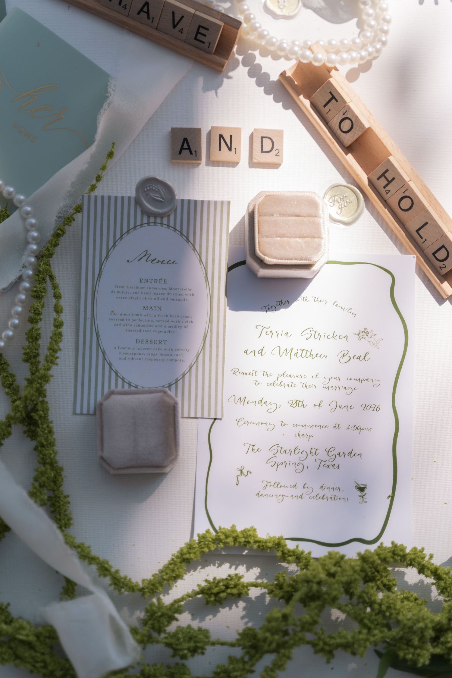 Wedding invitation suite with elegant calligraphy and greenery details on a white surface.
