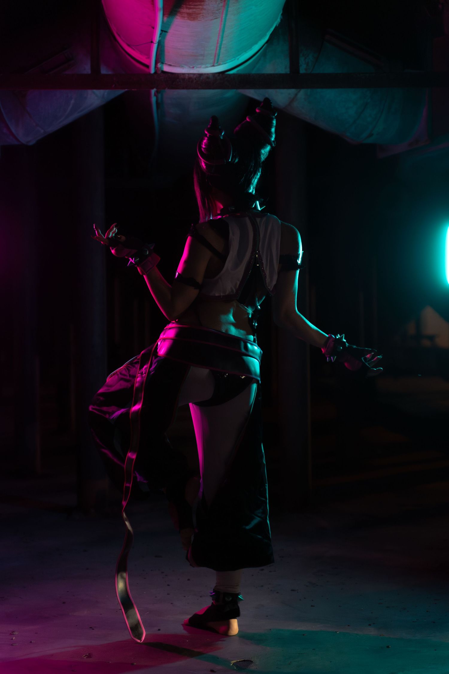 Silhouette of performer in dramatic pink and teal stage lighting.