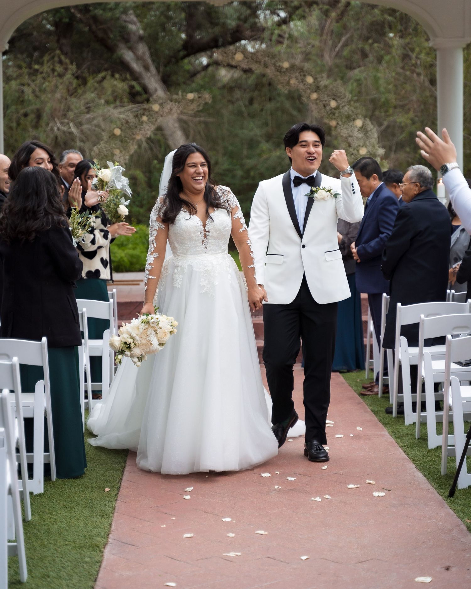 Wedding ceremony setup with white chairs and floral arrangements on outdoor path.