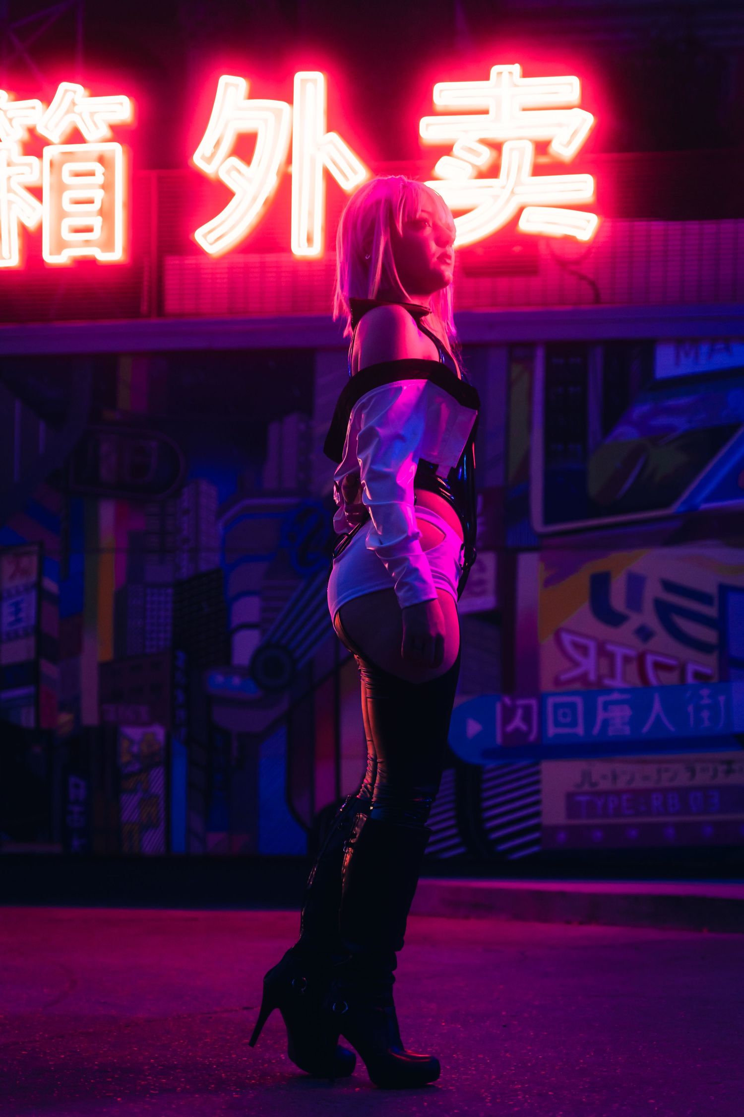 Woman in cyberpunk costume poses under neon Chinese signs at night in purple and pink lighting.
