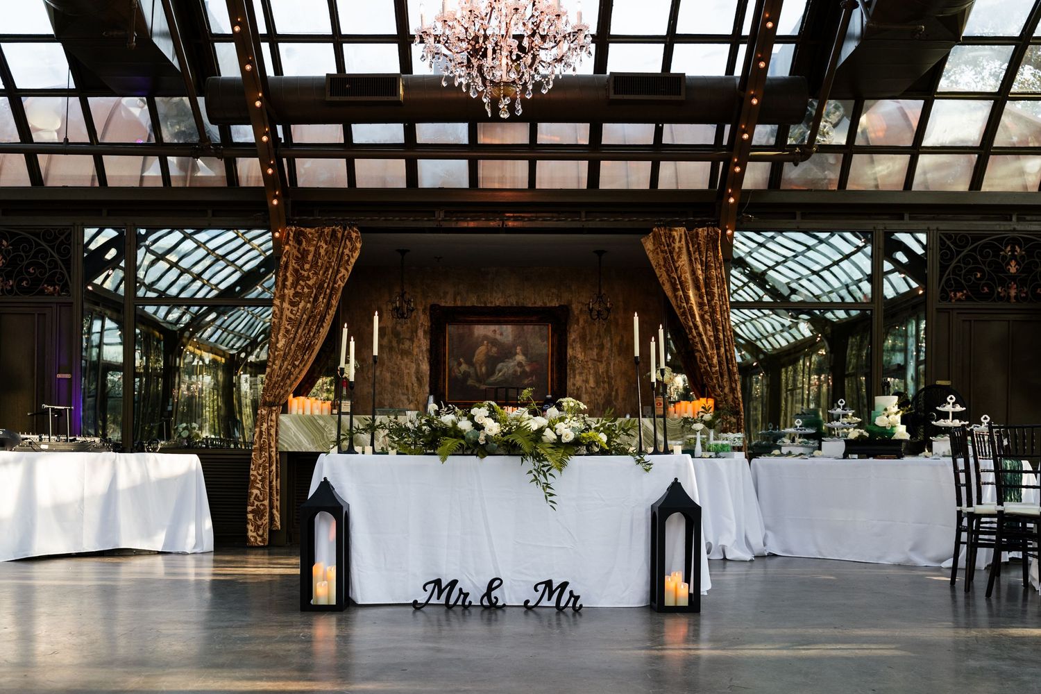A spacious wedding reception venue with glass ceiling and elegant table settings.