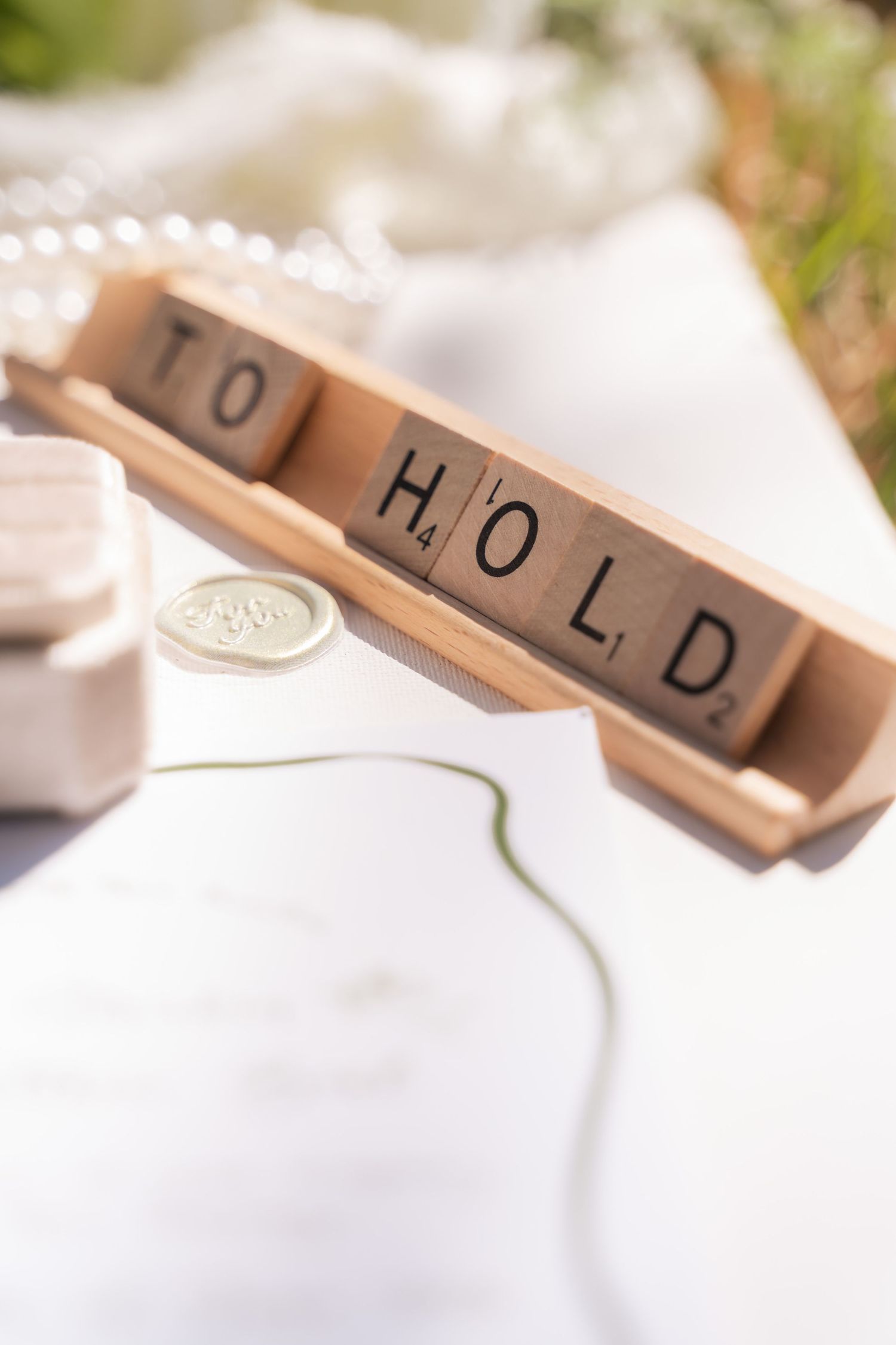 Wooden Scrabble tiles arranged artistically on white surface for wedding detail photography.