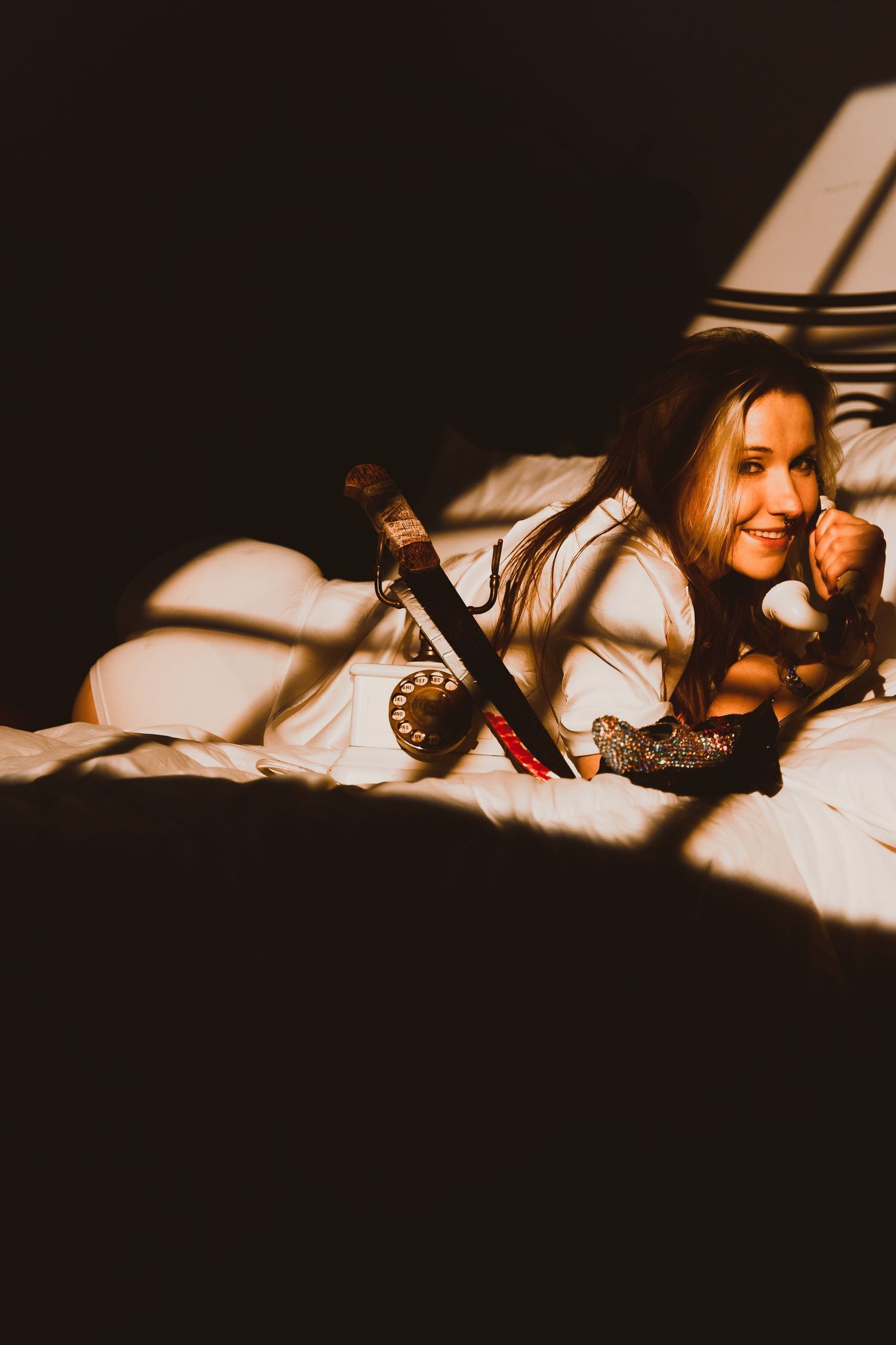 Artistic shadowy portrait of model lying on bed with dramatic lighting.