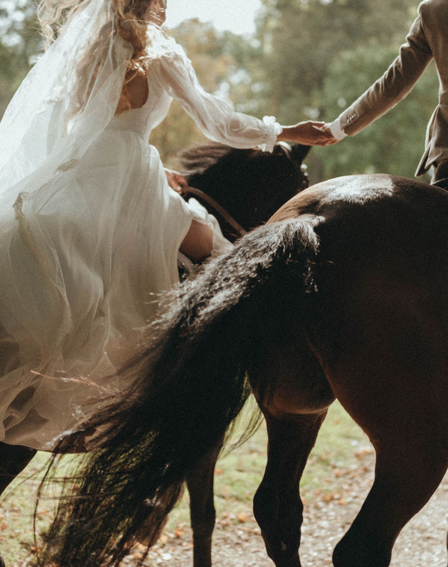 photographe mariage Angers mariés se tenant la main, tous deux à cheval, on voit le mouvement dans la robe de la mariée
