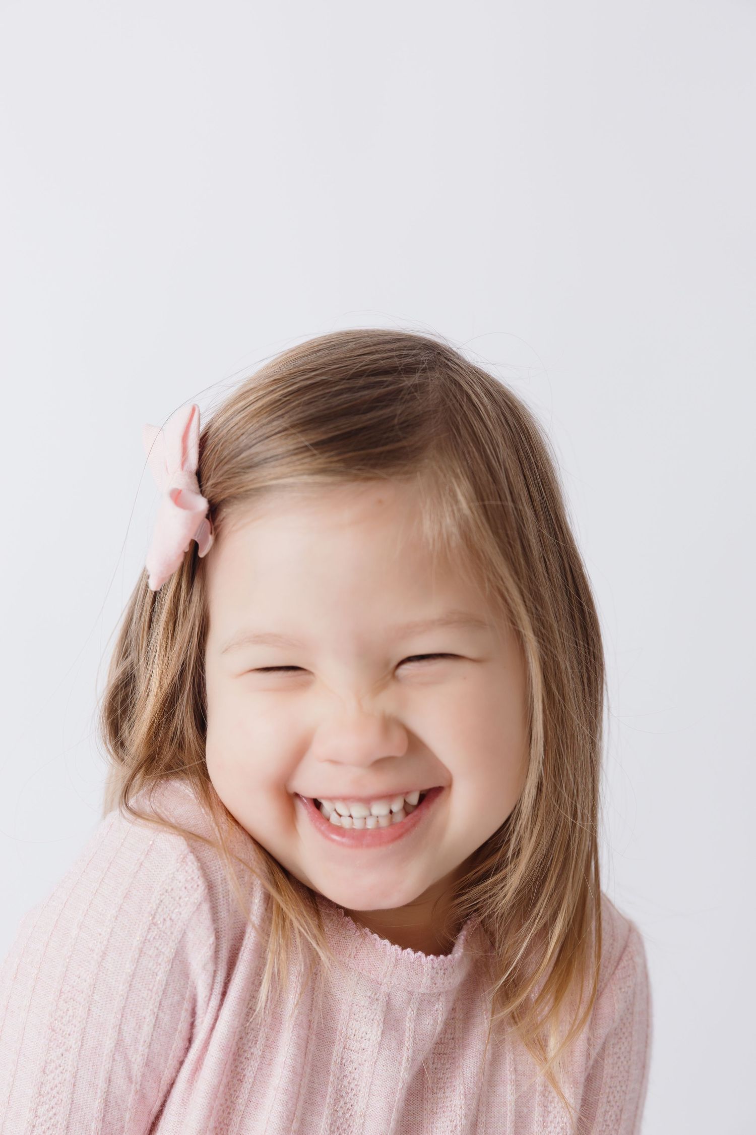 Candid smiling moments in soft pink sweater against white background.